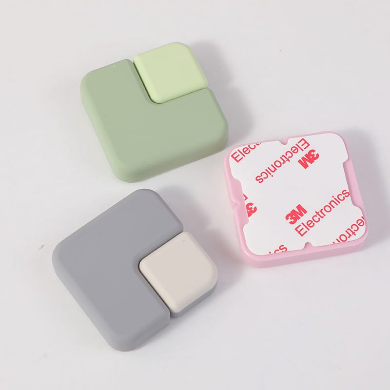 Tres protectores contra impactos cuadrados en tonos verde, gris y rosado con adhesivo posterior visible