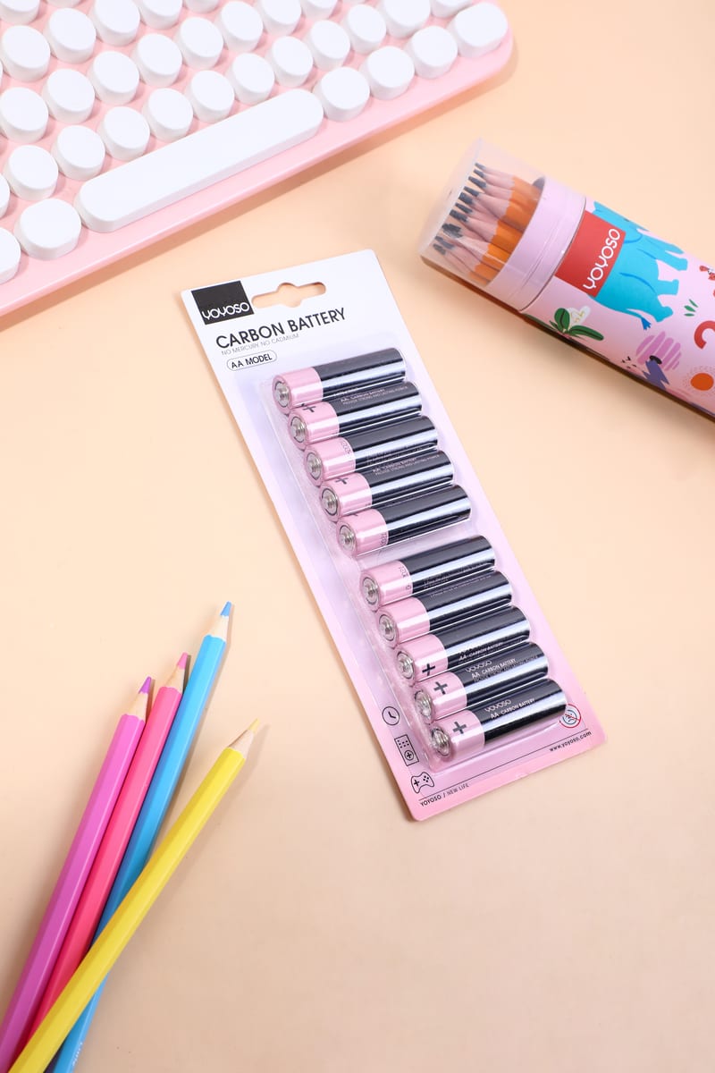 Empaque tipo blister con diez pilas AA en tono negro y rosa sobre un escritorio