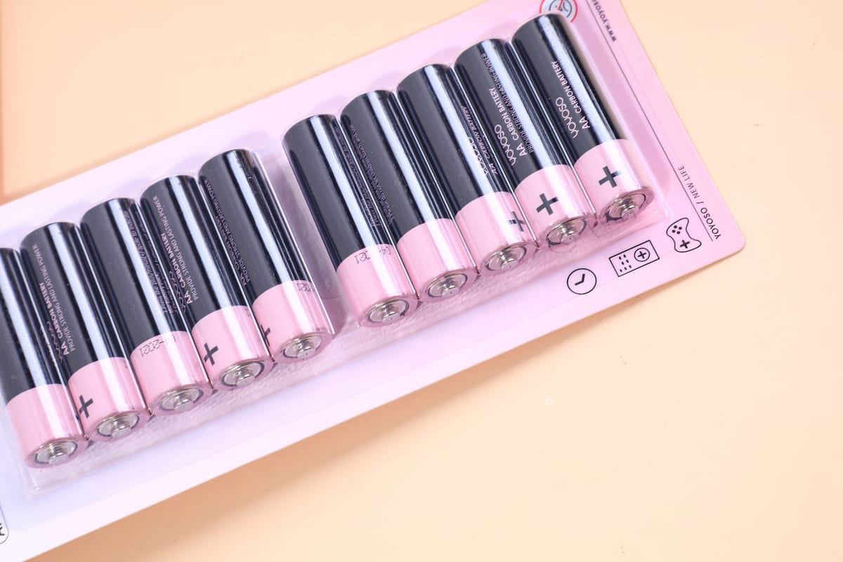 Detalle de diez pilas AA con cuerpo negro y extremos rosa en blister transparente
