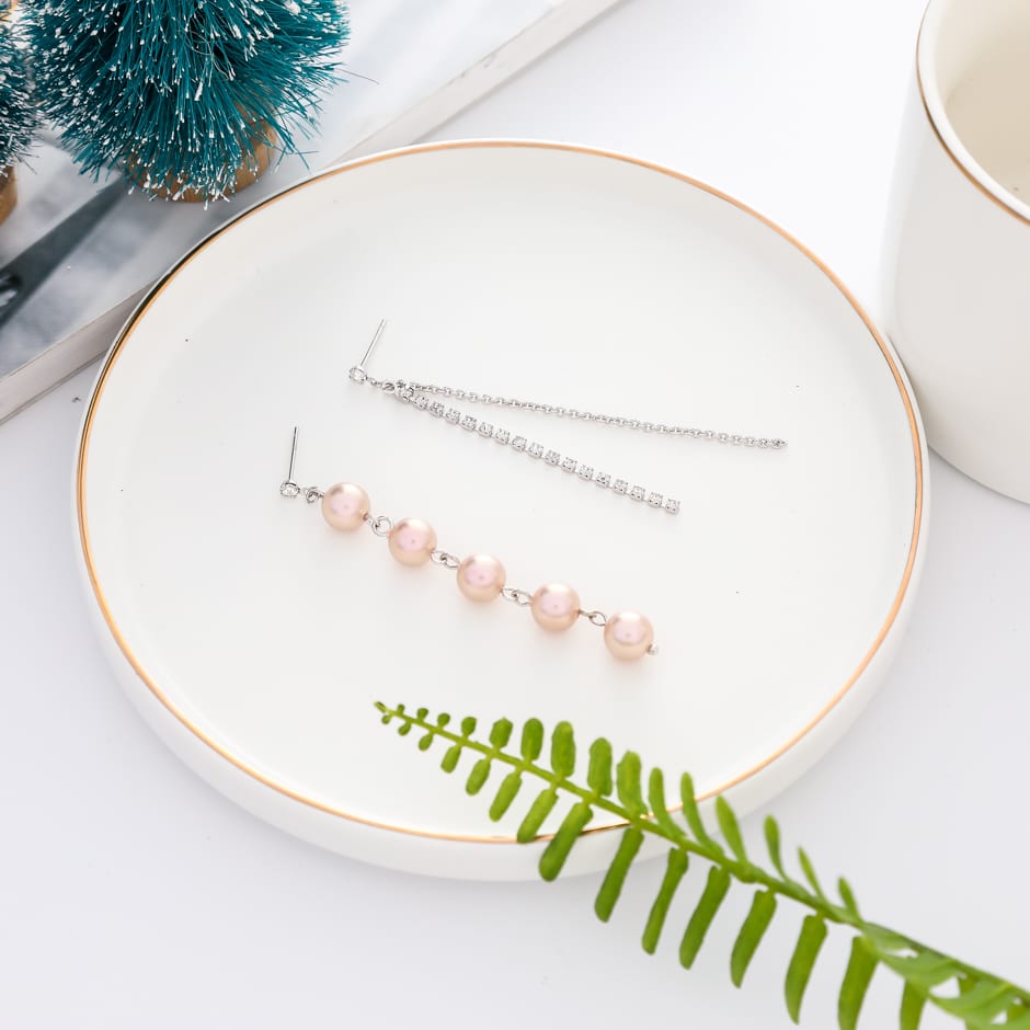 Aretes asimétricos plateados sobre un plato decorativo blanco
