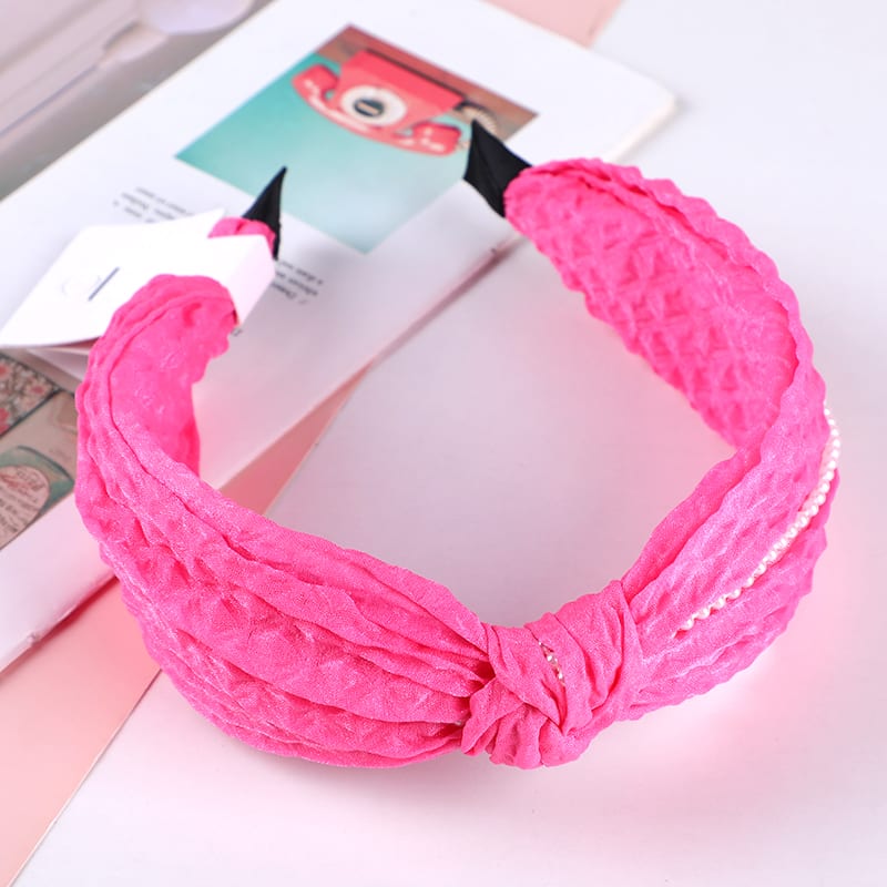 Diadema fucsia de tela corrugada con nudo central y tira de perlas blancas