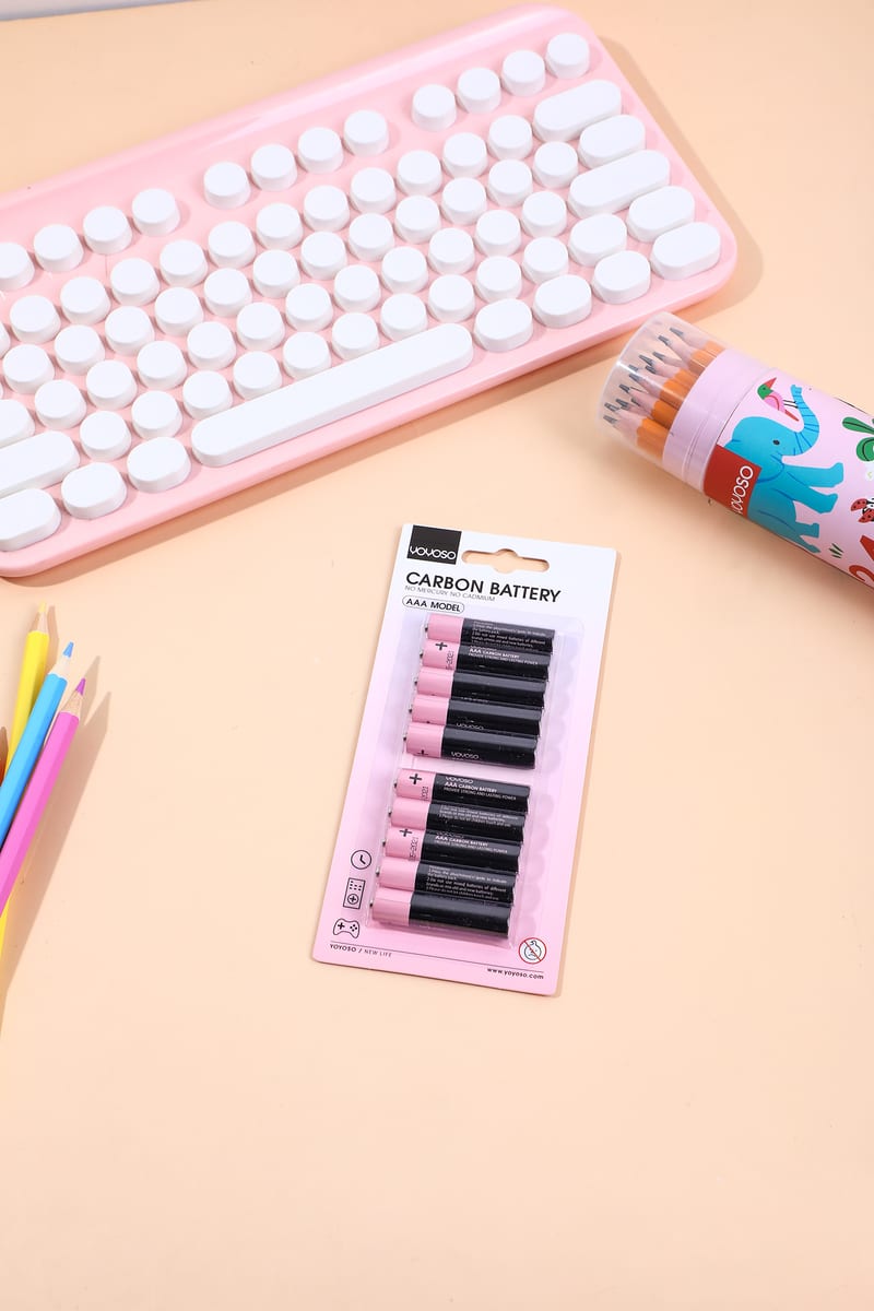 Paquete de 10 pilas AAA rosadas y negras sobre un escritorio junto a un teclado.