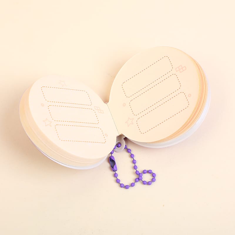 Mini libreta circular abierta mostrando hojas interiores con recuadros punteados y cadena metálica