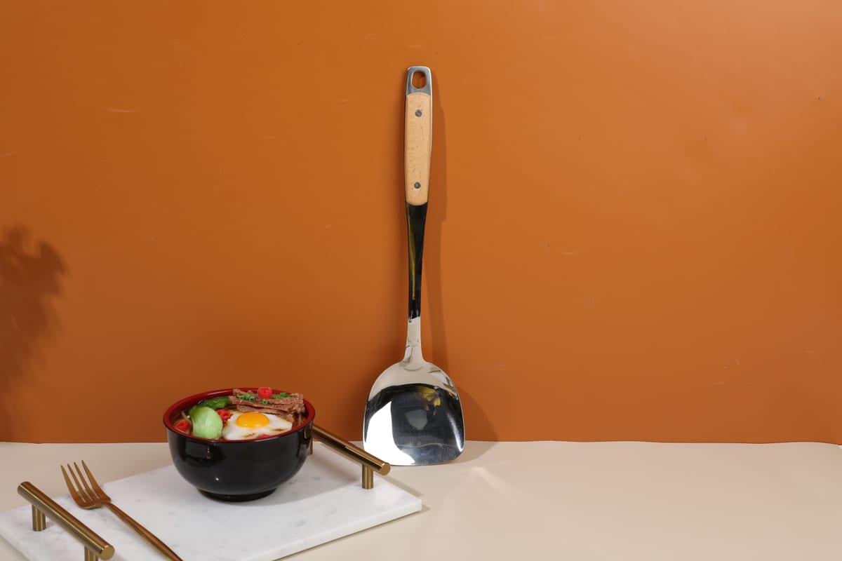 Espátula de cocina apoyada verticalmente junto a tazón sobre mesa clara
