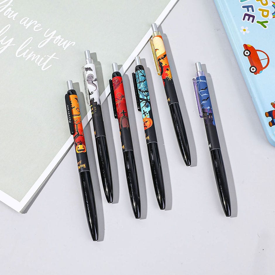 Seis esferos de gel con temática de Halloween desplegados sobre una libreta